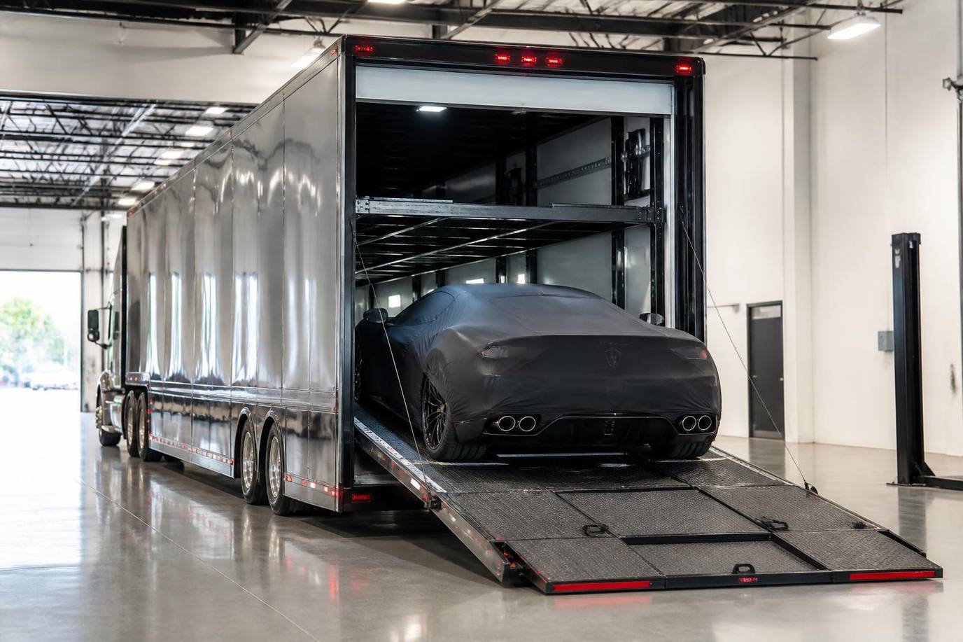 Enclosed semi-truck car carrier loading a covered exotic sports car